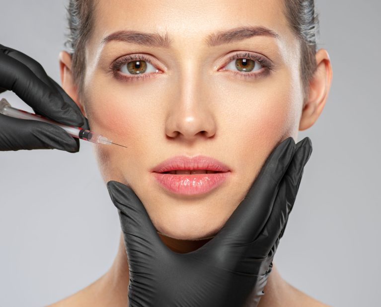 Young caucasian woman getting botox cosmetic injection near the eyes. Beautiful woman gets botox injection in her face. Adult girl gets cosmetic injection of botox in a clinic. Beauty treatments